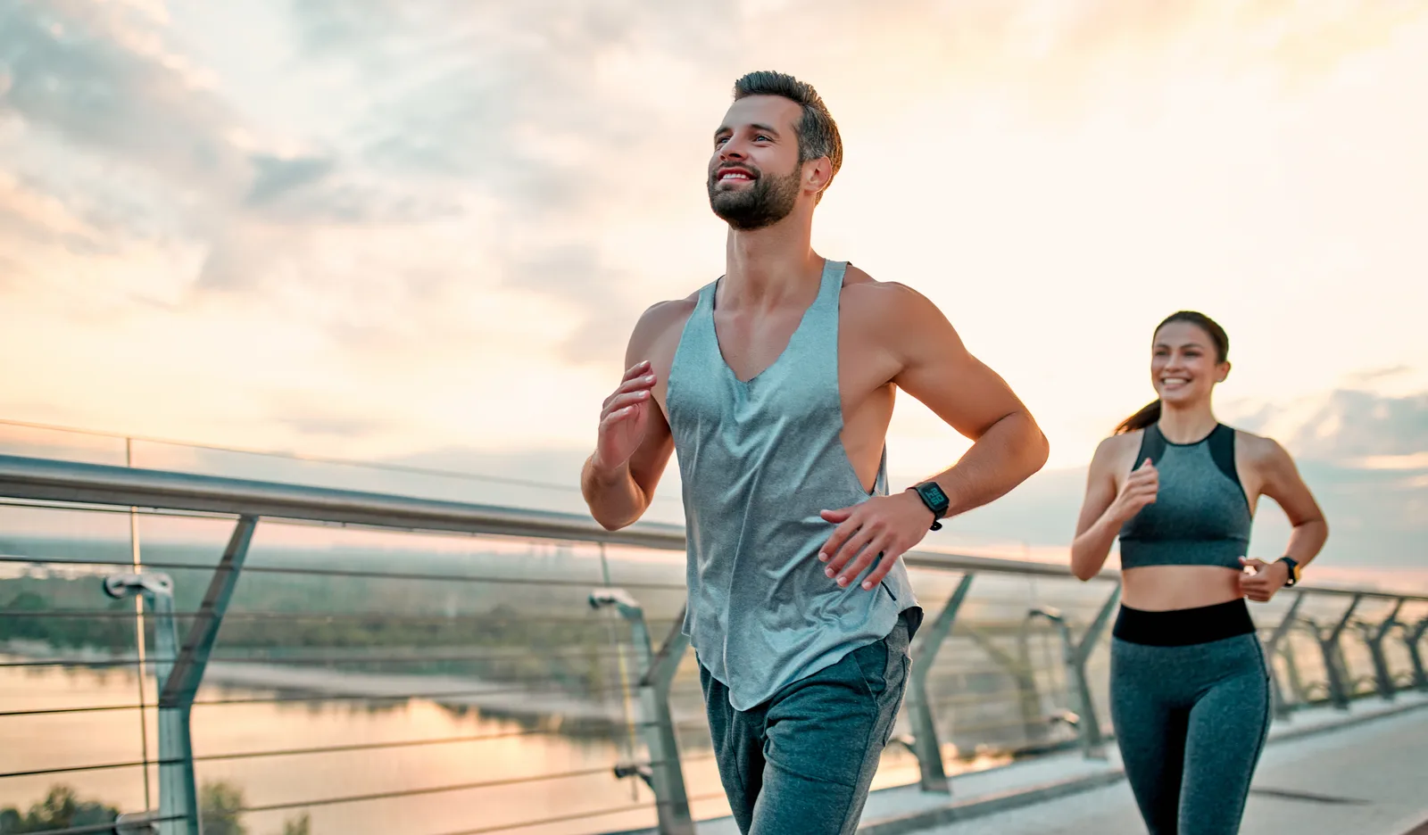 Career-peak couple jogging an urban bridge — Edgewater hormone and body composition care