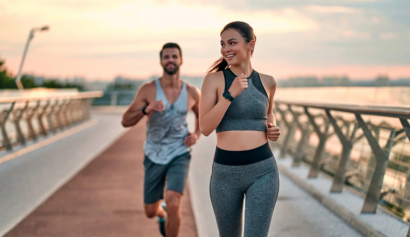 Active couple jogging across a Miami bridge at sunset, supported by hormone therapy and wellness care at Rewind Anti-Aging