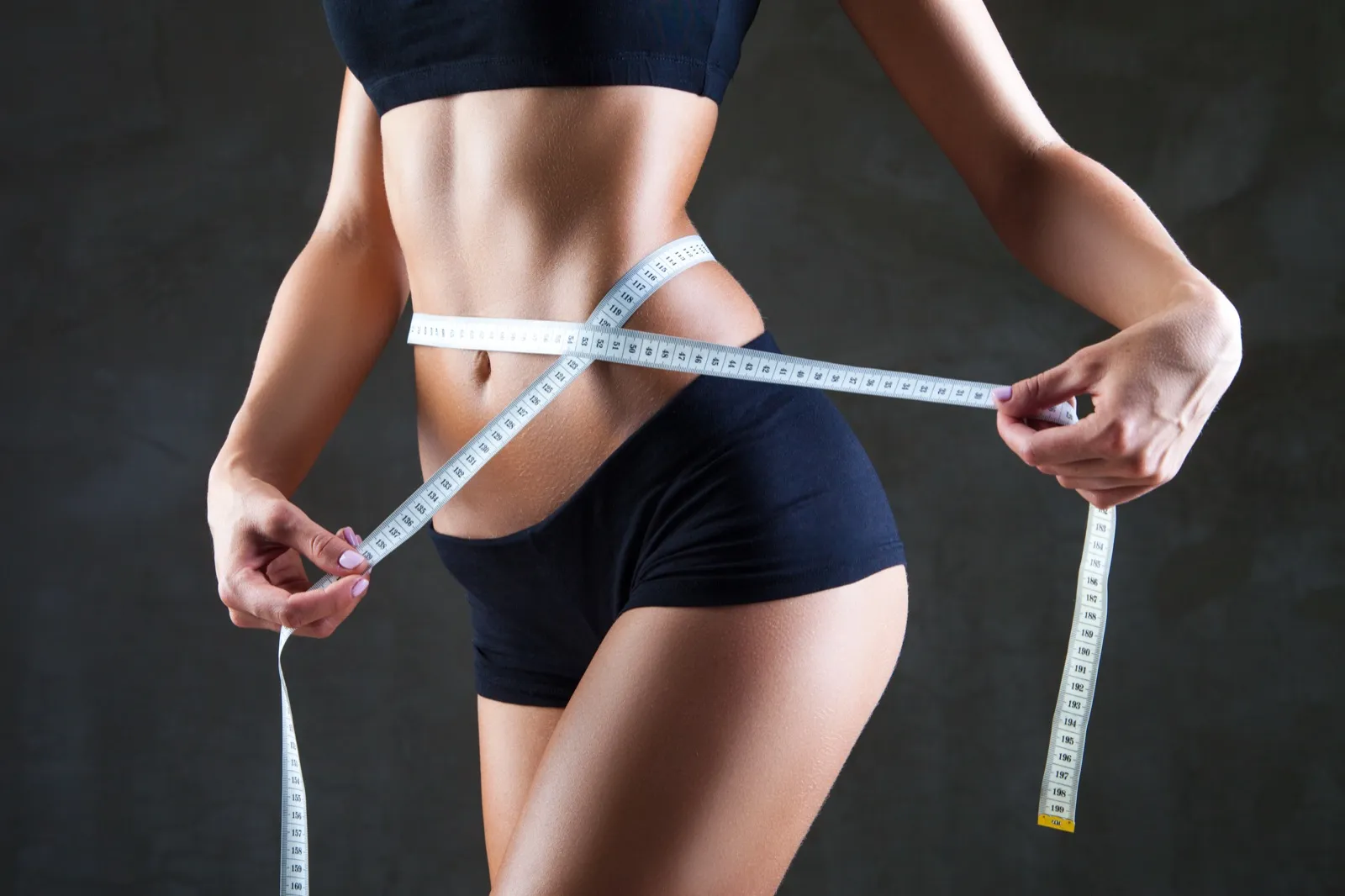 Woman measuring waist showing weight loss progress at Rewind Anti-Aging Miami